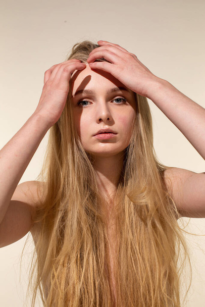 White young woman with blonde hair isolated on beige with hand near the face - Photo, Image