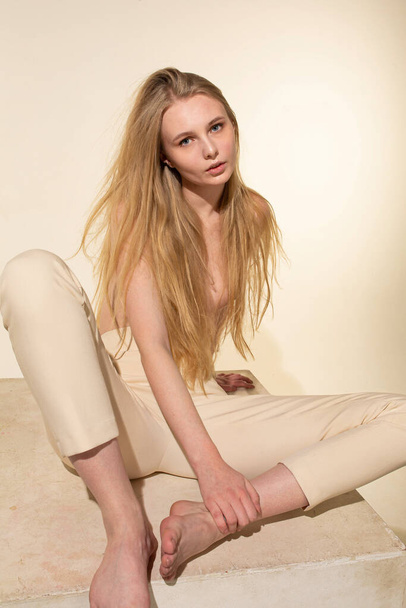 European white young woman with blonde hair isolated on beige sitting - Φωτογραφία, εικόνα