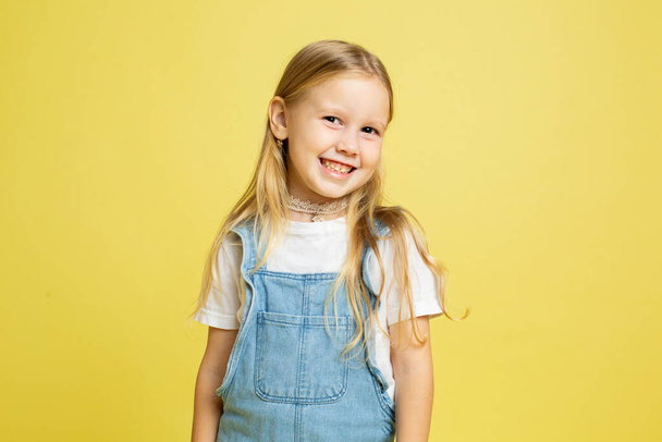 Smiling baby girl with blonde hair isolated on yellow - Foto, Imagem