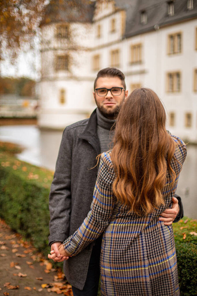 Young european married couple with building behind in park in autumn - Fotografie, Obrázek
