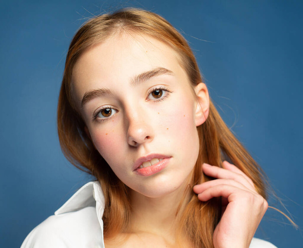 Girl with red hair and white skin isolated on blue closeup portrait - 写真・画像