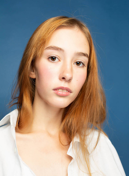 Closeup portrait girl with red hair and white skin isolated on blue - Φωτογραφία, εικόνα
