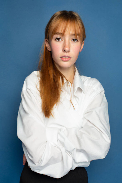 Bright young girl with red hair and white skin isolated on blue portrait - Фото, изображение