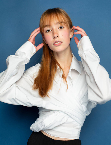 Bright young girl with red hair and white skin isolated on blue in blouse - Foto, afbeelding