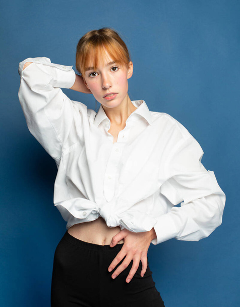 Girl with red hair and white skin isolated on blue in white blouse - Foto, afbeelding