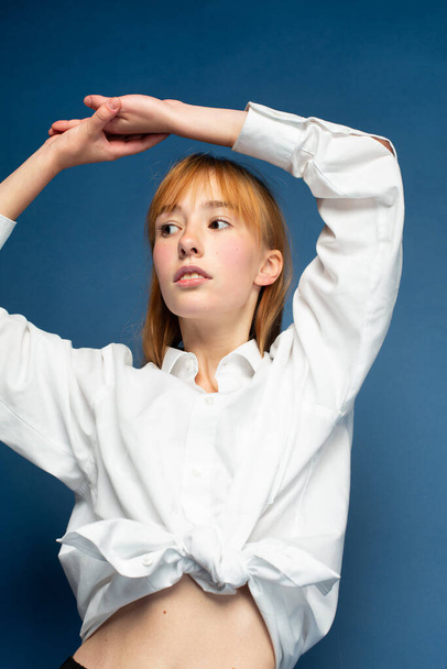 Young girl with red hair and white skin isolated on blue in white shirt - Foto, Bild