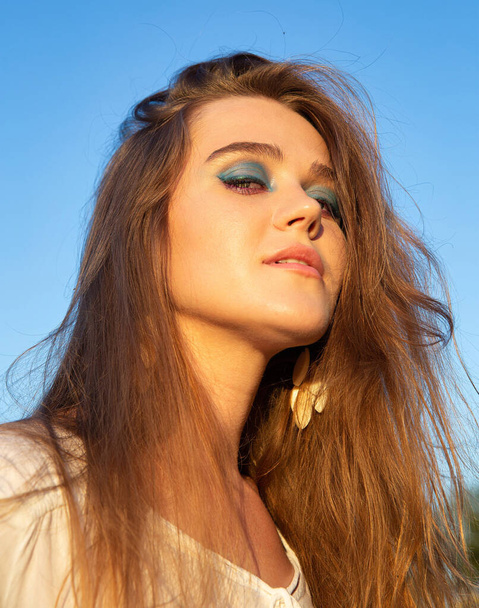 Portrait of young woman with white skin with sky behind with blue eyeshadow makeup - Fotografie, Obrázek