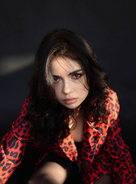 Portrait of young dark haired woman with white skin on dark background in leopard print clothes - Foto, imagen