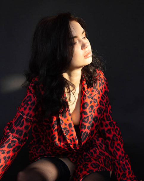 Portrait of young dark haired woman with white skin on dark background in leopard print clothes - Foto, immagini