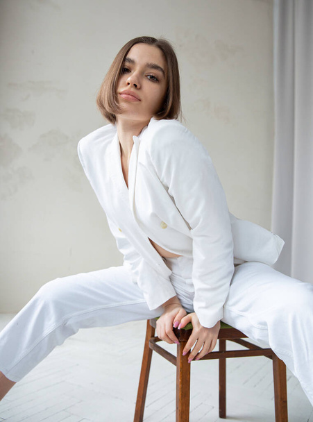 White european woman with bob cut sitting on chair in white business suit - Foto, Imagem