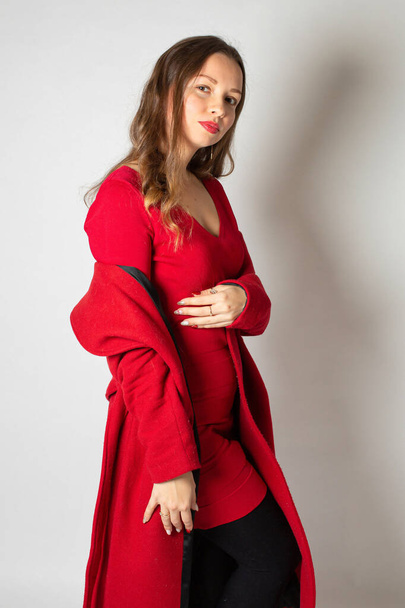 Attractive young european woman in red coat isolated on light grey - Photo, Image