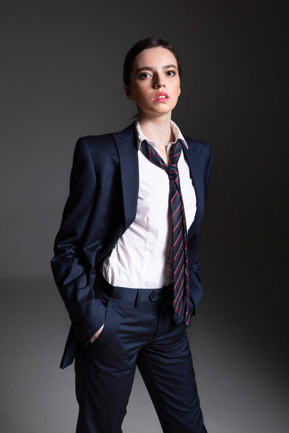 European young woman in black man suit isolated on dark grey with hands in pocket - Fotoğraf, Görsel