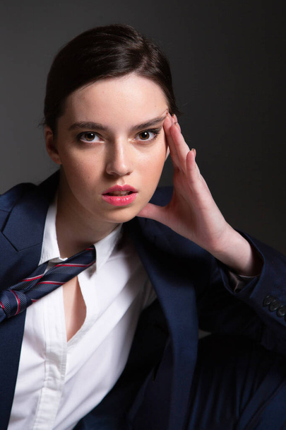 Portrait in business style of european young woman in black man suit with dark hair isolated on dark grey - Foto, immagini