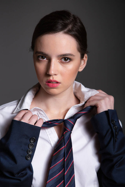 Portrait in business style of european young woman in white shirt wearing man tie isolated on black with plump lips - Foto, Imagen
