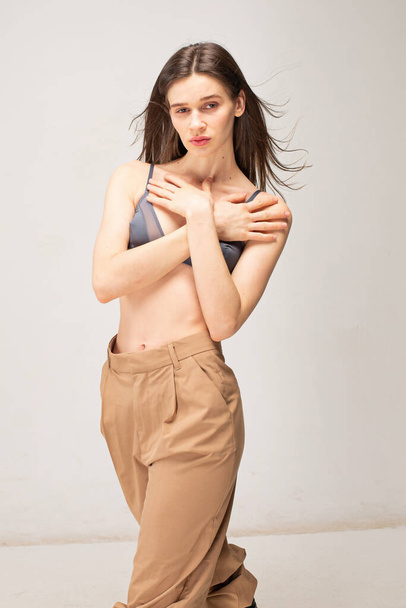 Young slim woman with dark straight hair isolated on beige with crossed arms on her chest - Foto, Bild