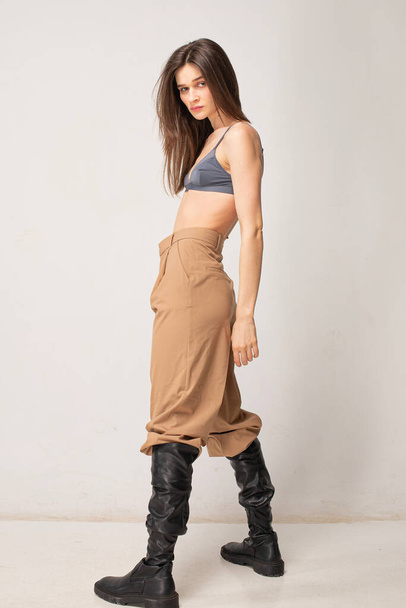 Young slim woman with dark straight hair isolated on beige in full length - Фото, зображення