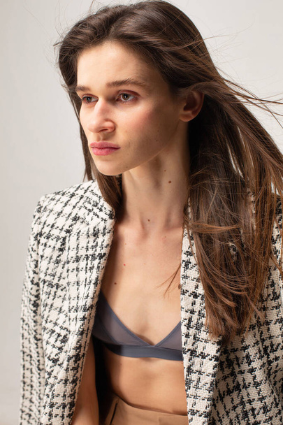 Young slim woman with dark straight hair portrait in plaid blazer - Zdjęcie, obraz