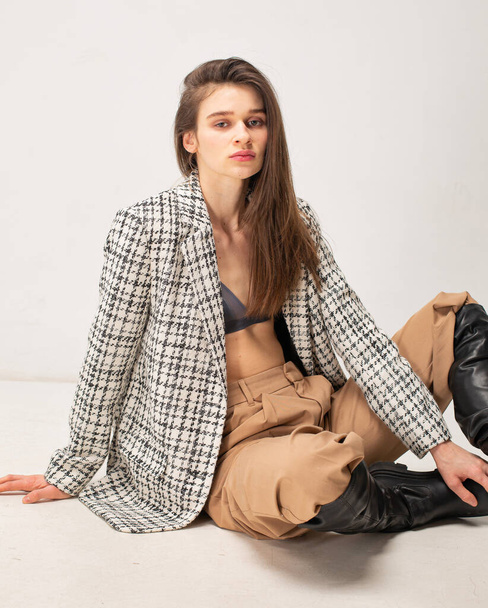 Young slim woman with dark hair isolated on light beige in plaid blazer - Foto, immagini