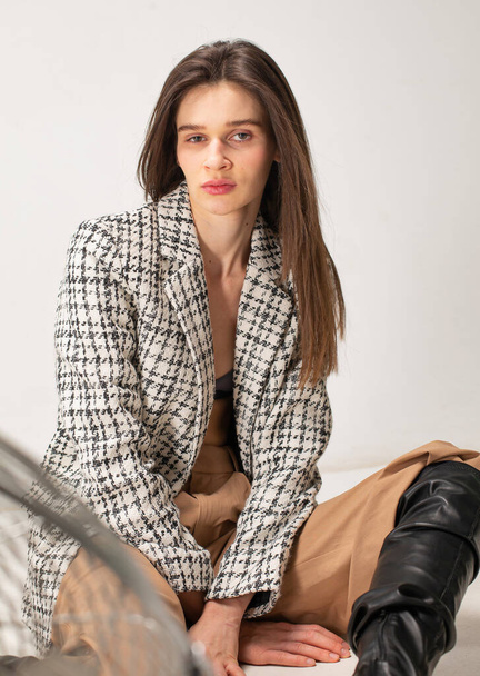 Young slim woman with dark hair isolated on light beige in plaid blazer - Photo, Image