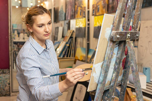 Art - a young woman paints a picture in a workshop - Foto, imagen