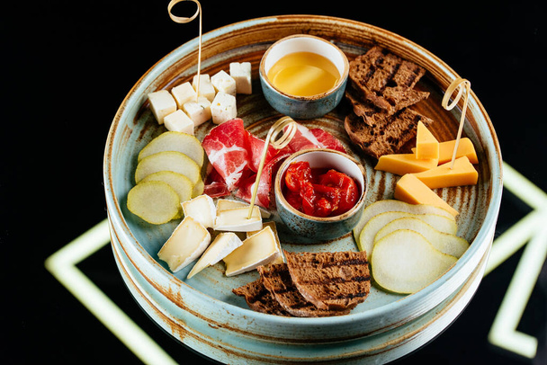 leckere Snacks mit Fleisch und Gemüse auf schwarzem Hintergrund - Foto, Bild