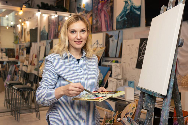 Una joven artista comienza a pintar un cuadro en un estudio de arte - Foto, imagen
