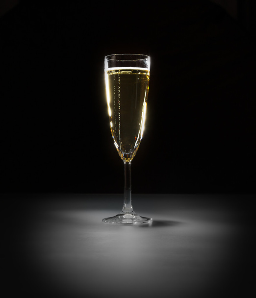 Elegant glass of vine with bubbles on the black background on light spot - Фото, изображение