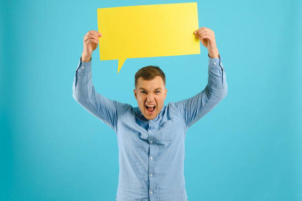 Handsome smiling man holding blank speech bubble sign isolated on light blue studio banner background with copy space - Φωτογραφία, εικόνα