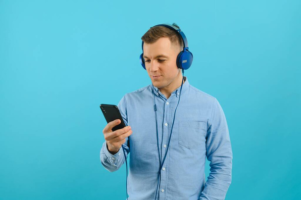 Handsome young man listening to music on color background - Foto, Imagen
