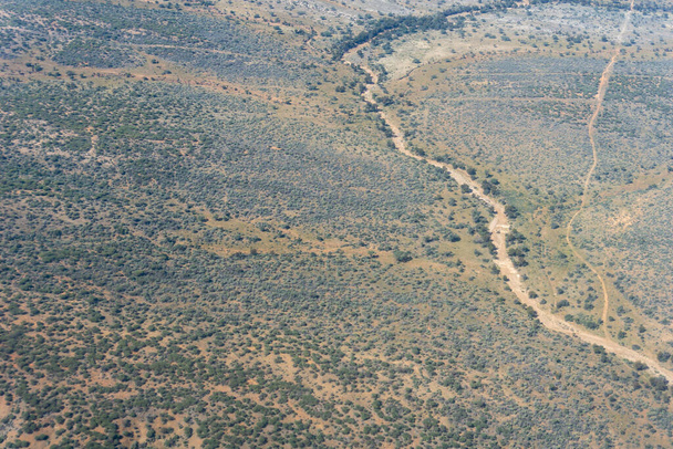 Letecký pohled Namibijská krajina se zaprášenými cestami potkává suché koryto řeky v akátovém keři roztroušené krajiny. - Fotografie, Obrázek