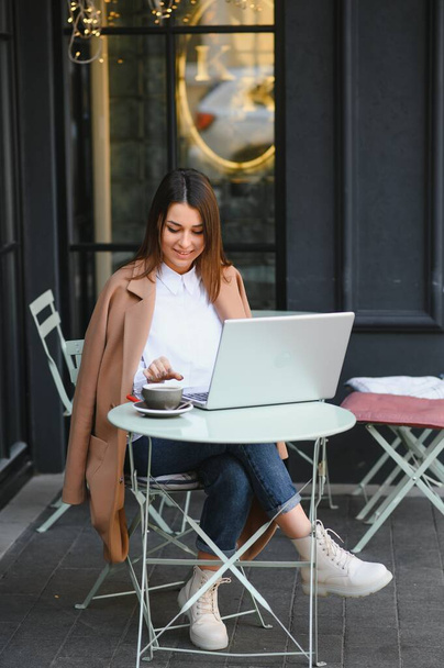Foto portret van prachtige aantrekkelijke vrouw werken op laptop typen zitten in cafe het drinken van koffie - Foto, afbeelding