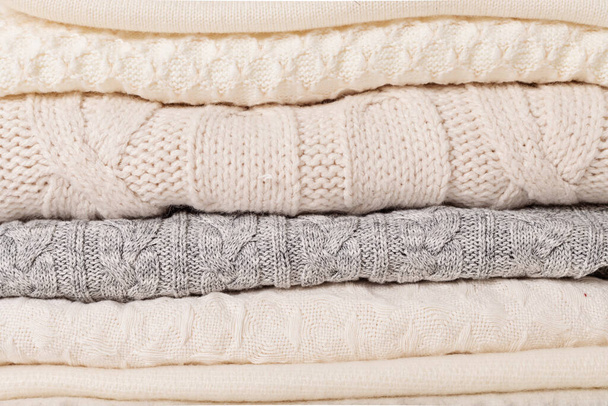 Pile of cozy white knitted clothes for cold weather.  Comfort organic sweaters. Hygge style idea - Foto, imagen