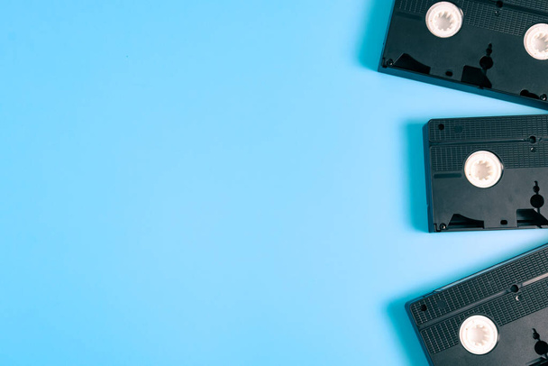 Three retro videotapes lie on the right against a blue background with copy space on the left, top view, close-up. Cinema concept. - Foto, afbeelding