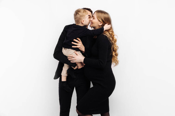 Happy family spend time together. pregnant woman, her husband and little son are talking and smiling while spending time together on white background. Parenthood concept, pregnancy, family - Photo, image