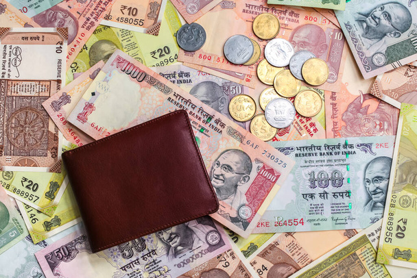 Leather wallet with 1000 rupees note and other Indian notes and coins of different value on background - Foto, imagen