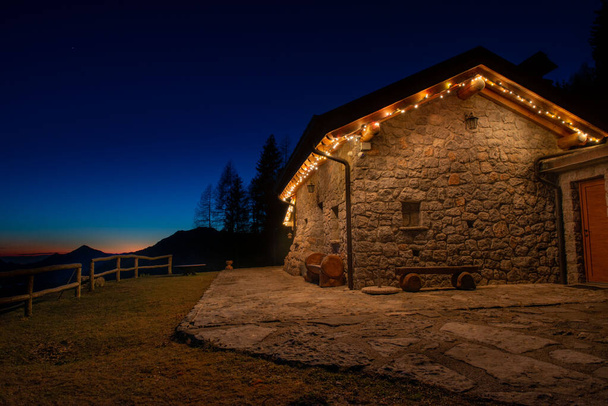 Πέτρινο εξοχικό σπίτι στο βουνό φωτίζεται με τεχνητό φως, - Φωτογραφία, εικόνα