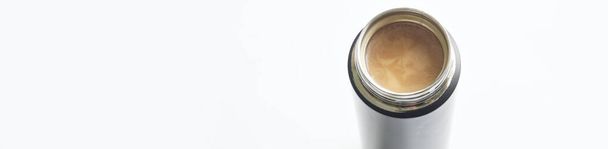 Open metal thermos or thermo mug with hot coffee and cream. White background. View from above. Free space for an inscription. Web banner. Selective focus. Close-up - Photo, Image
