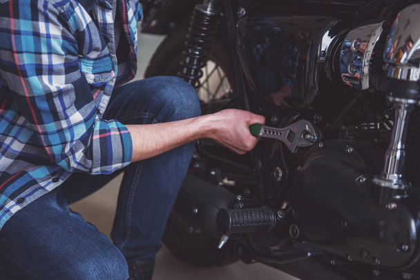 Alkalmi ruhák-vonzó szőke férfi javítása egy motorkerékpár, közeli - Fotó, kép