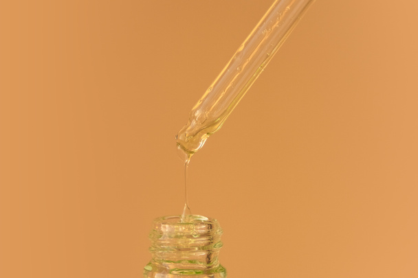 Πιπέτα με πράσινο υγρό υαλουρονικό οξύ ή ορό σε μπεζ φόντο. Καλλυντικά και υγειονομική περίθαλψη έννοια closeup - Φωτογραφία, εικόνα