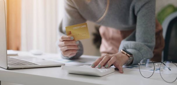Lähikuva nainen tarkistaa laskuja, verot, pankkitilin saldo ja laskettaessa luottokortilla kulut kotona - Valokuva, kuva