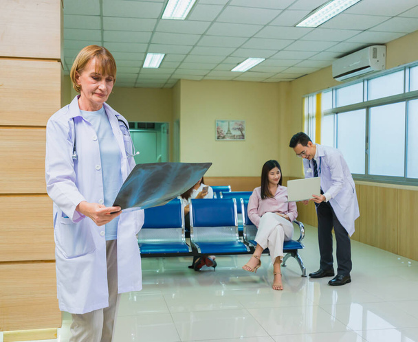 Doktor kadınlar hastanedeki hastanın sağlık röntgenlerini, steteskop tedavisi gören doktorları kontrol eder. - Fotoğraf, Görsel