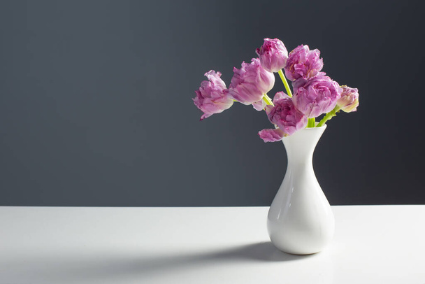 violet tulips in white vase on background gray wall - Φωτογραφία, εικόνα