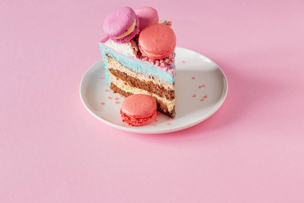 piece of cake with pink and blue decor on white plate on pink background - Foto, Bild