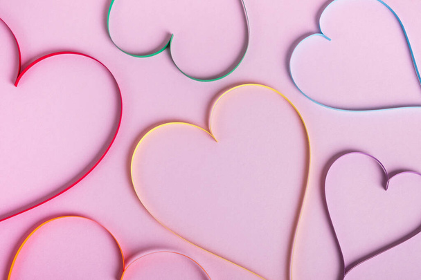 Сердца в цветах радуги на пастельно-фиолетовом фоне. День Святого Валентина, ЛГБТ и концепция любви. Вид сверху, плоский - Фото, изображение