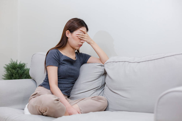 Žena, která má depresi, sedí sama na gauči. Žena s tváří zakrytou bolestí hlavy. nešťastná emoce. - Fotografie, Obrázek
