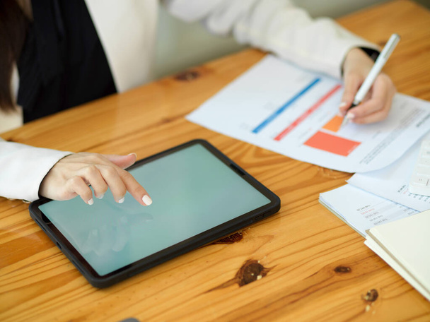 Gesneden beeld van een vrouwelijke werknemer met behulp van digitale tablet touchscreen en werken aan marketing onderzoeksrapport in het kantoor. - Foto, afbeelding