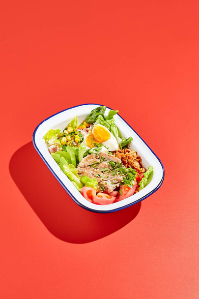 American cobb salad with chicken, eggs and vegetables in minimal style. Healthy salad on trend red background with hard shadow. Bowl with salad, chicken, eggs, vegetables in contemporary style - Valokuva, kuva