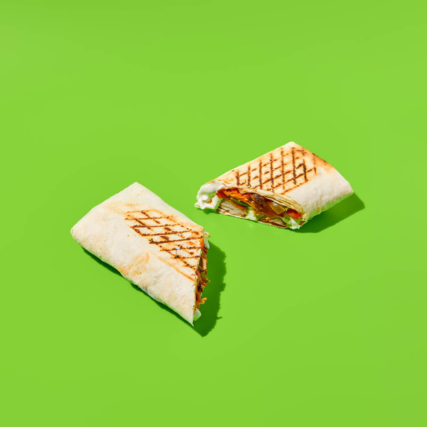 Shawarma with vegetables and meat on green background. Contemporary poster with shawarma. Doner kebab in minimal style. Street food concept. Junk food design. Minimalistic fast food menu - Fotografie, Obrázek