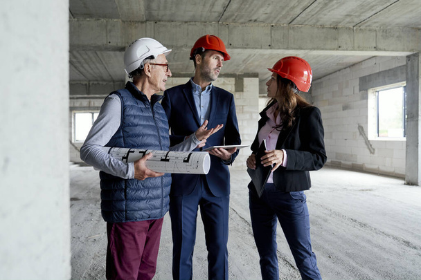 Medium shot of group of  caucasian engineers and investors discussing on construction site  - Foto, afbeelding