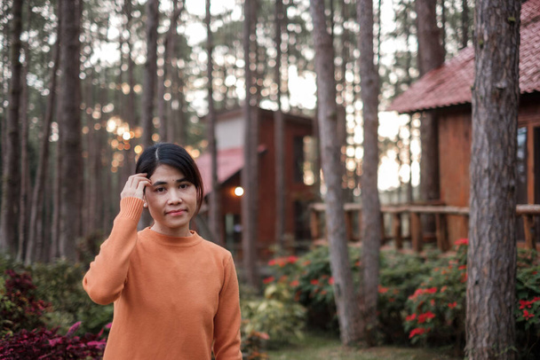 Happy woman in sweater traveling in pine tree forest, tourist visit at Doi Bo Luang, Chiang Mai, Thailand, Landmark and popular for tourist attractions. Vacation and journey concept - Фото, изображение